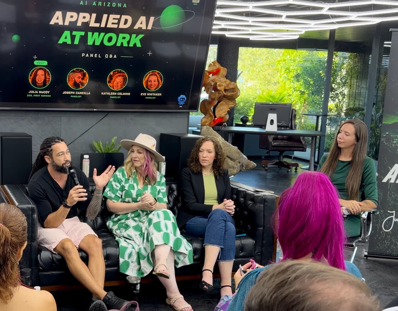 Joseph speaking into a microphone on the Applied AI at Work panel at AI Arizona, seated beside three other panelists.